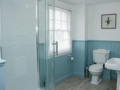 a bathroom with a toilet and a glass shower at Troutbeck Cottage in Ludlow
