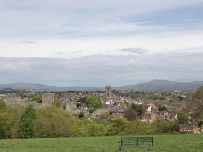 a bench sitting on a hill overlooking a city at Troutbeck Cottage in Ludlow
