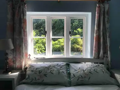 a bedroom with a bed with three windows at Craig Fach Coach House in Builth Wells