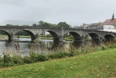 a stone bridge with arches over a river at Craig Fach Coach House in Builth Wells