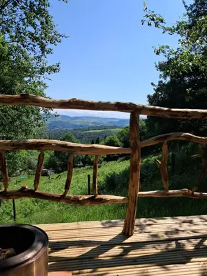 a wooden deck with a view of a field at Hilltop Train Carriage with a View in Machynlleth