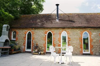 two white chairs and a table in front of a brick building at The Hornbill at Home Farm Shropshire in Shrewsbury