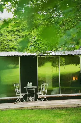two chairs and a table on a patio with a house at The Hornbill at Home Farm Shropshire in Shrewsbury