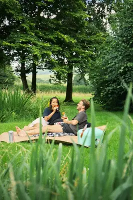 two people sitting on a blanket in the grass at The Hornbill at Home Farm Shropshire in Shrewsbury