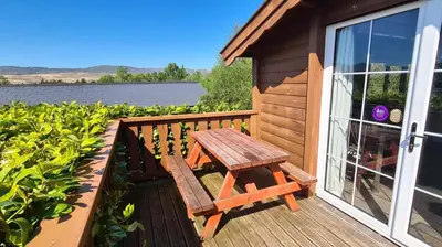 a wooden bench sitting on the deck of a house at Cosy log cabin in Snowdonia 167 in Trawsfynydd