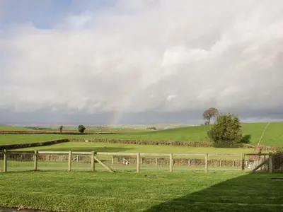 a rainbow in the sky over a field with a fence at White House in Montgomery