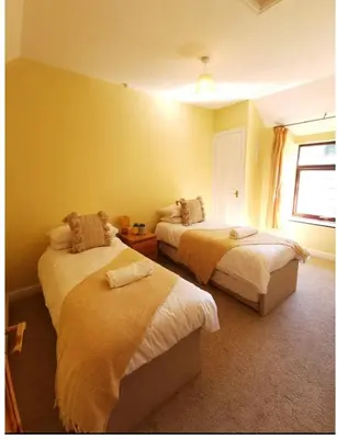 a bedroom with two beds and a window at Glanyrafon Cottage in Sennybridge