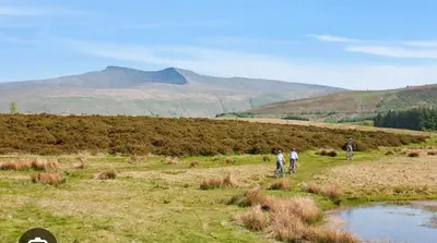 three people riding bikes in a field with mountains in the background at Glanyrafon Cottage in Sennybridge