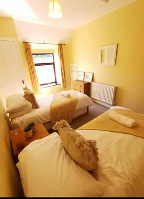 a bedroom with three beds and a window at Glanyrafon Cottage in Sennybridge