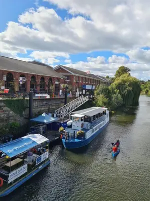 two boats are docked in a river next to a building at Cosy Corner - Town centre flat with free nearby parking in Shrewsbury