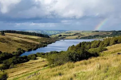 a rainbow over a river in the middle of a field at Happy Horse Cottages in Sennybridge