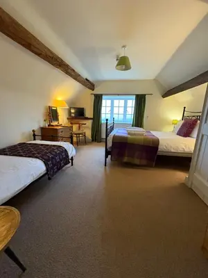 a bedroom with two beds and a desk in it at The Harp Inn in Old Radnor