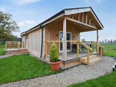 a wooden cabin with a porch and a deck at Llwynog Lodge in Montgomery