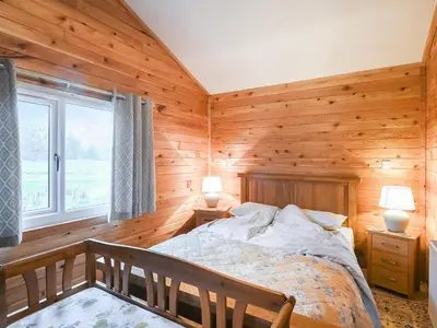 a bedroom with wooden walls and a bed and a window at Llwynog Lodge in Montgomery