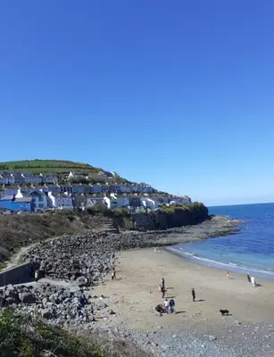 a group of people on a beach near the ocean at Newquay Haven caravan 42x14 with Ocean Views in New Quay