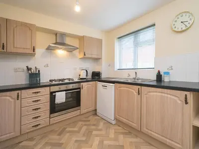 a kitchen with wooden cabinets and a clock on the wall at 3 bedroom detached homesleeps 5 in Shrewsbury - Pass the Keys in Bicton