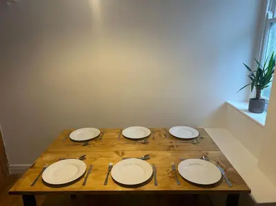 a wooden table with four white plates and forks and knives at Charming newly renovated 3 bed cottage in Brecon town with private garden & pets welcome in Brecon