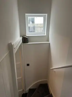 a small white room with a window and a staircase at Charming newly renovated 3 bed cottage in Brecon town with private garden & pets welcome in Brecon