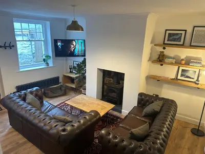 a living room with a leather couch and a table at Charming newly renovated 3 bed cottage in Brecon town with private garden & pets welcome in Brecon