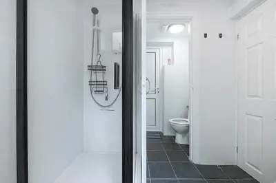 a white bathroom with a toilet and a door at 2 Bed Ground Floor Beach Location in Aberdyfi