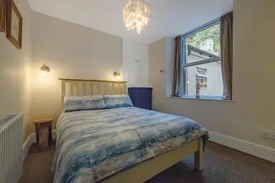 a bedroom with a bed and a window and a chandelier at 2 Bed Ground Floor Beach Location in Aberdyfi