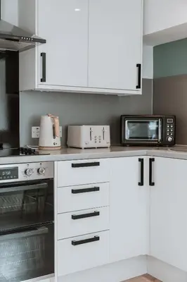 a kitchen with white cabinets and a microwave at 2 Bed Apartment Overlooking the Square Step Out to Shops & Dining in Shrewsbury