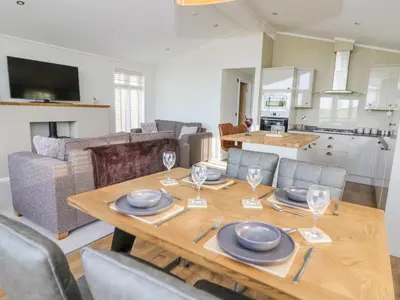a dining room with a table and a kitchen at Seren Lodge in Builth Wells