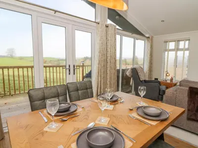 a dining room with a table and chairs and windows at Seren Lodge in Builth Wells