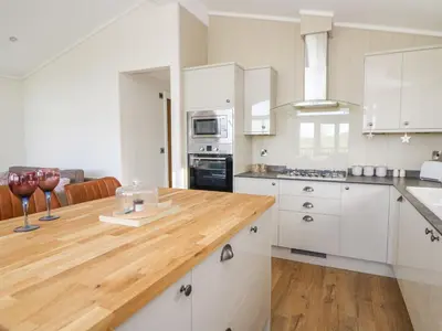 a kitchen with white cabinets and a wooden counter top at Seren Lodge in Builth Wells