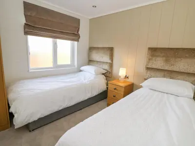 two beds in a small bedroom with a window at Seren Lodge in Builth Wells
