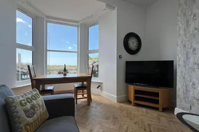 a living room with a table and a clock on the wall at Barmouth beach ground level in Barmouth