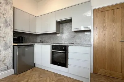 a kitchen with white cabinets and a dishwasher at Barmouth beach ground level in Barmouth