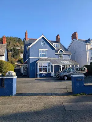 a blue house with a car parked in a parking lot at Cartref Guesthouse - Room 2 Ensuite in Aberdyfi