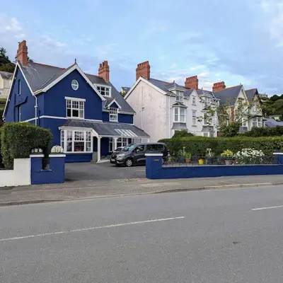 a blue house with a car parked in a parking lot at Cartref Guesthouse - Room 2 Ensuite in Aberdyfi