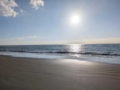 a beach with the sun rising over the ocean at Cartref Guesthouse - Room 2 Ensuite in Aberdyfi