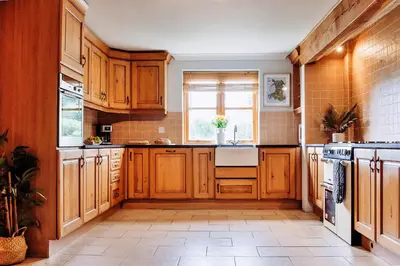 a kitchen with wooden cabinets and a window at Finest Retreats - The Welsh Farmhouse in Aberystwyth