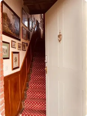 a hallway with a staircase with red carpet at The Coach House in Berriew