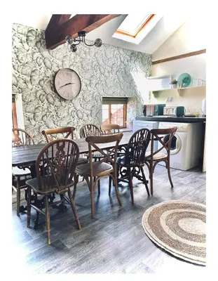 a dining room table with chairs and a clock on the wall at The Coach House in Berriew