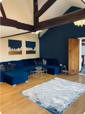 a living room with a blue couch and a rug at The Coach House in Berriew