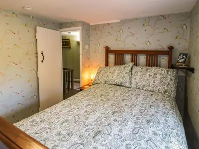 a bedroom with a bed in a room with wallpaper at River Cottage in Llanbedr