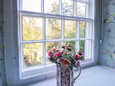 a vase of flowers sitting in front of a window at River Cottage in Llanbedr