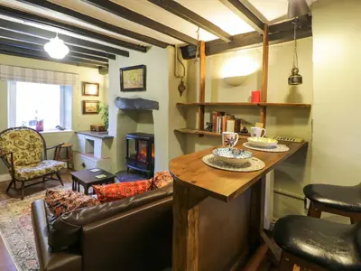 a living room with a table and a fireplace at River Cottage in Llanbedr
