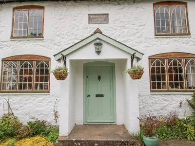 a white house with a green door and windows at Rowan Cottage in Bishops Castle