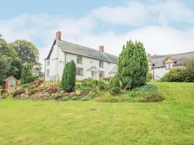 an old white house with trees in the yard at Rowan Cottage in Bishops Castle