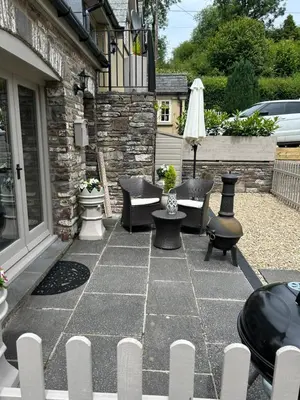 a patio with chairs and a table and an umbrella at Cosy riverside property in Aber-Brân