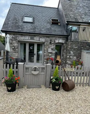 a house with a fence and potted plants in front of it at Cosy riverside property in Aber-Brân