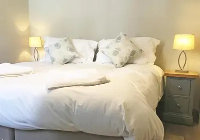 a bed with white sheets and pillows and two lamps at The Royal Oak, Gladestry in Gladestry