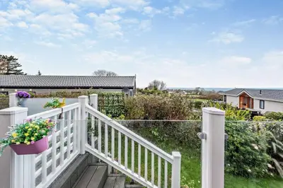 a white fence with a porch with flowers on it at Coogee View Lodge in New Quay