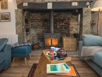 a living room with a stone fireplace and a table at Cosy cottage hideaway set in beautiful countryside - Pass the Keys in Hopesay