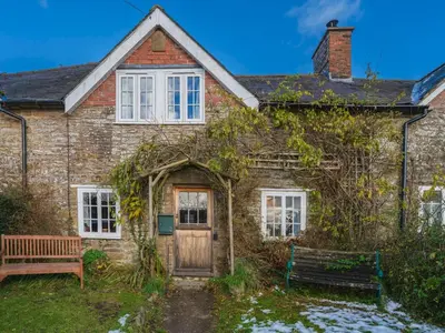 an old brick house with a wooden door and a bench at Cosy cottage hideaway set in beautiful countryside - Pass the Keys in Hopesay